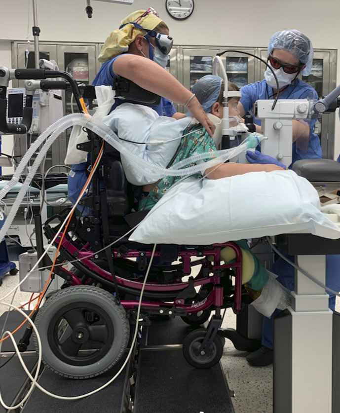 A 5-year-old child undergoing sedated Nd:YAG laser posterior capsulotomy in an upright position in the operating room setting with the aid of an Invacare Spree 3G Pediatric Tilt-in-Space Wheelchair